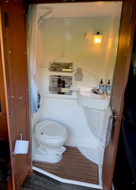 Compact RV rental bathroom with toilet, sink, and shower. Essential amenities visible for a comfortable trip.
