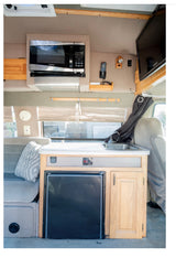 RV rental interior with microwave, TV, compact kitchen sink, refrigerator, and comfortable seating.