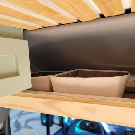RV rental interior shows wooden bed slats, an open cabinet, and fabric storage bins, optimizing space inside.