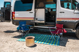 Storyteller Overland RV rental. Camper van with open door, chairs, mat, & fire pit for outdoor living. Adventure ready!
