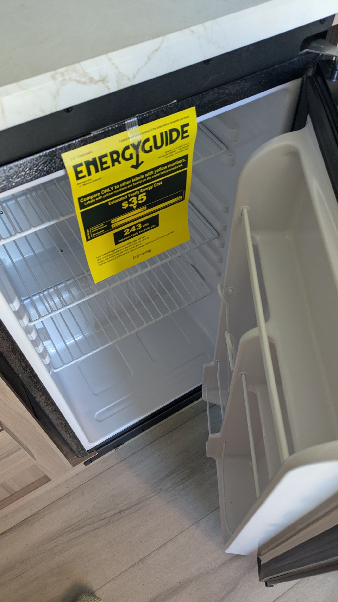 Inside an rv rental mini-fridge displaying its Energy Guide label, showing a $35 estimated yearly cost and 243 kWh use.