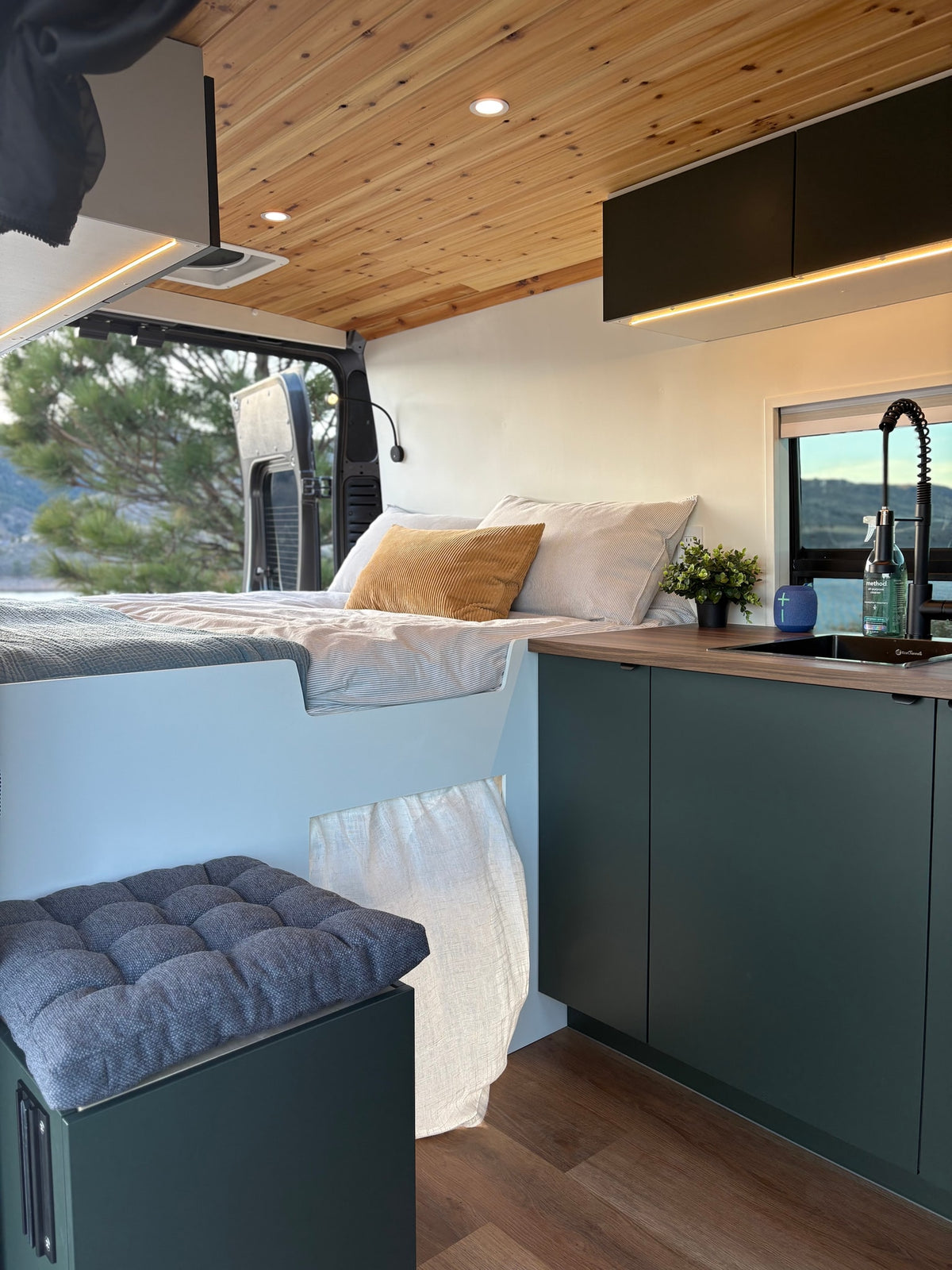 RV rental: Cozy camper van interior with a bed, kitchen, wooden ceiling, and scenic window view for travel. — photo 6