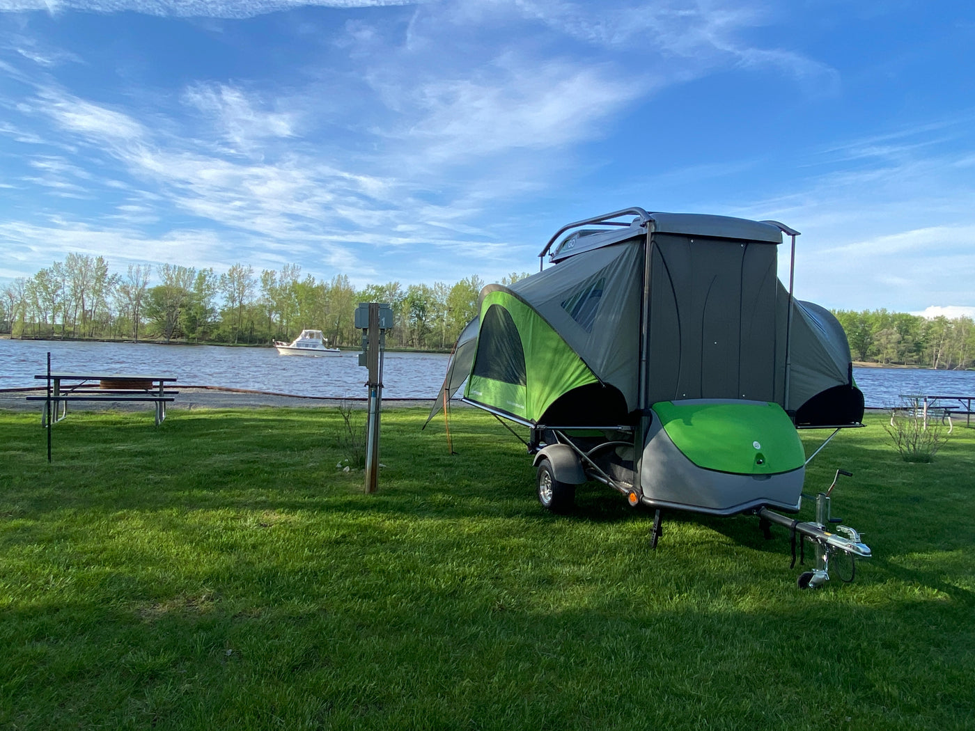 Compact pop-up RV rental by the river: a unique camping setup on a grassy site with a distant boat and trees. — photo 9