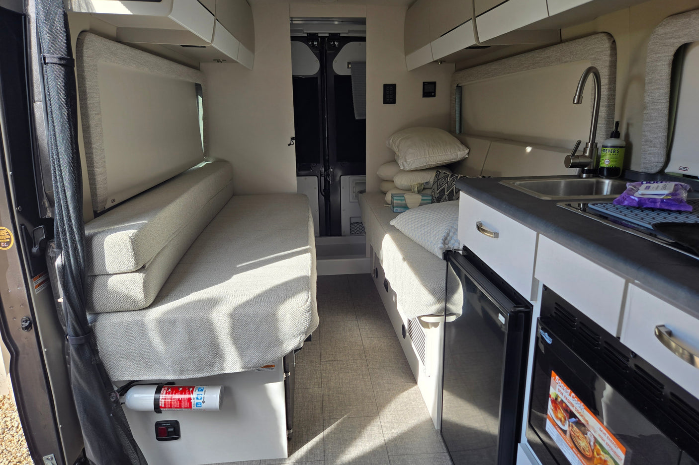 An RV rental interior with a compact kitchen, convertible seating/beds, and storage, perfect for your next road trip.