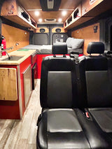Step inside this RV rental's camper van interior. Features a bright red kitchen, wood accents, and a cozy bed area.