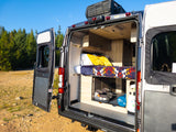 Compact RV rental camper van interior: bed, storage, child seat, ready for outdoor adventure.