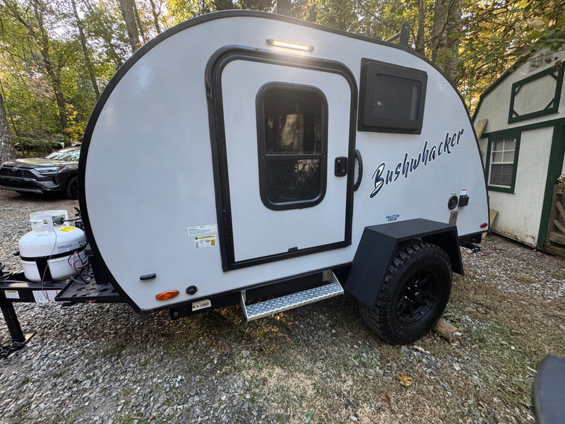 This light grey Bushwhacker teardrop camper makes a great RV rental, parked on gravel for outdoor adventures. — photo 10