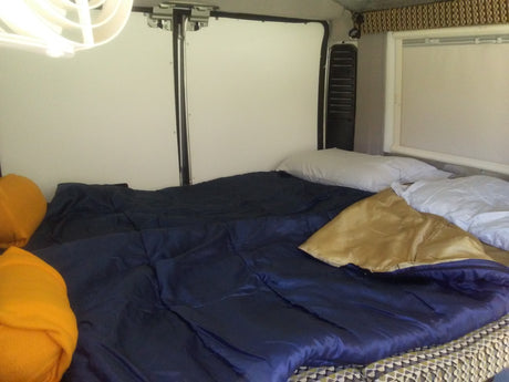 Comfortable RV rental bed setup with blue and gold bedding, perfect for a road trip adventure.