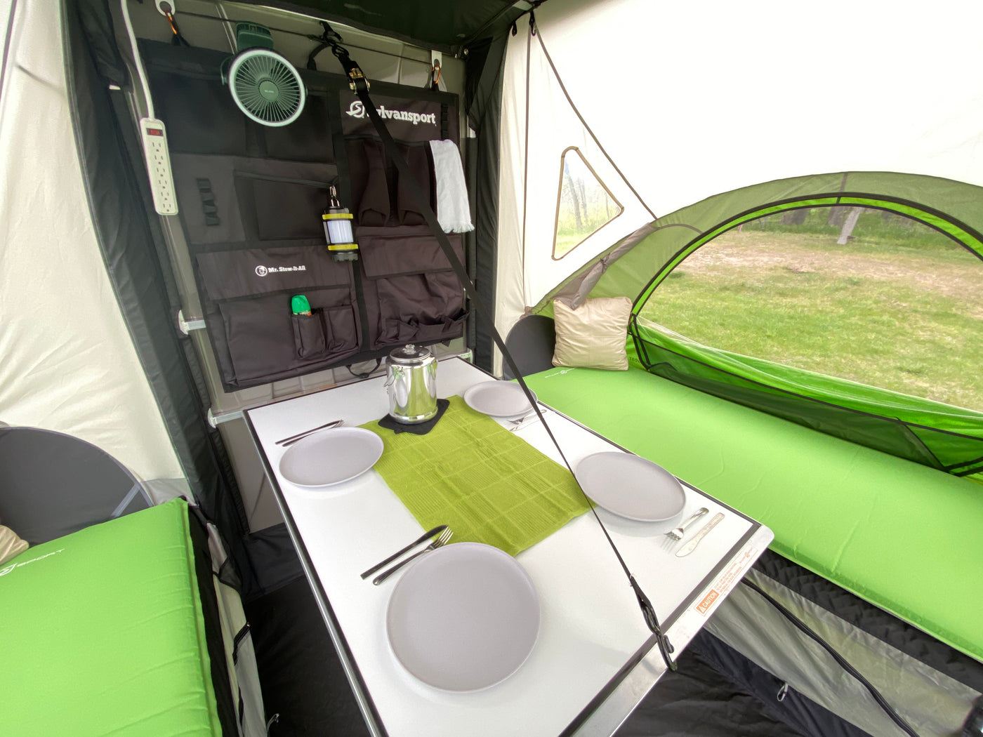 Organized RV rental interior features dining table, comfy sleeping pads, and wall storage for camping. — photo 14