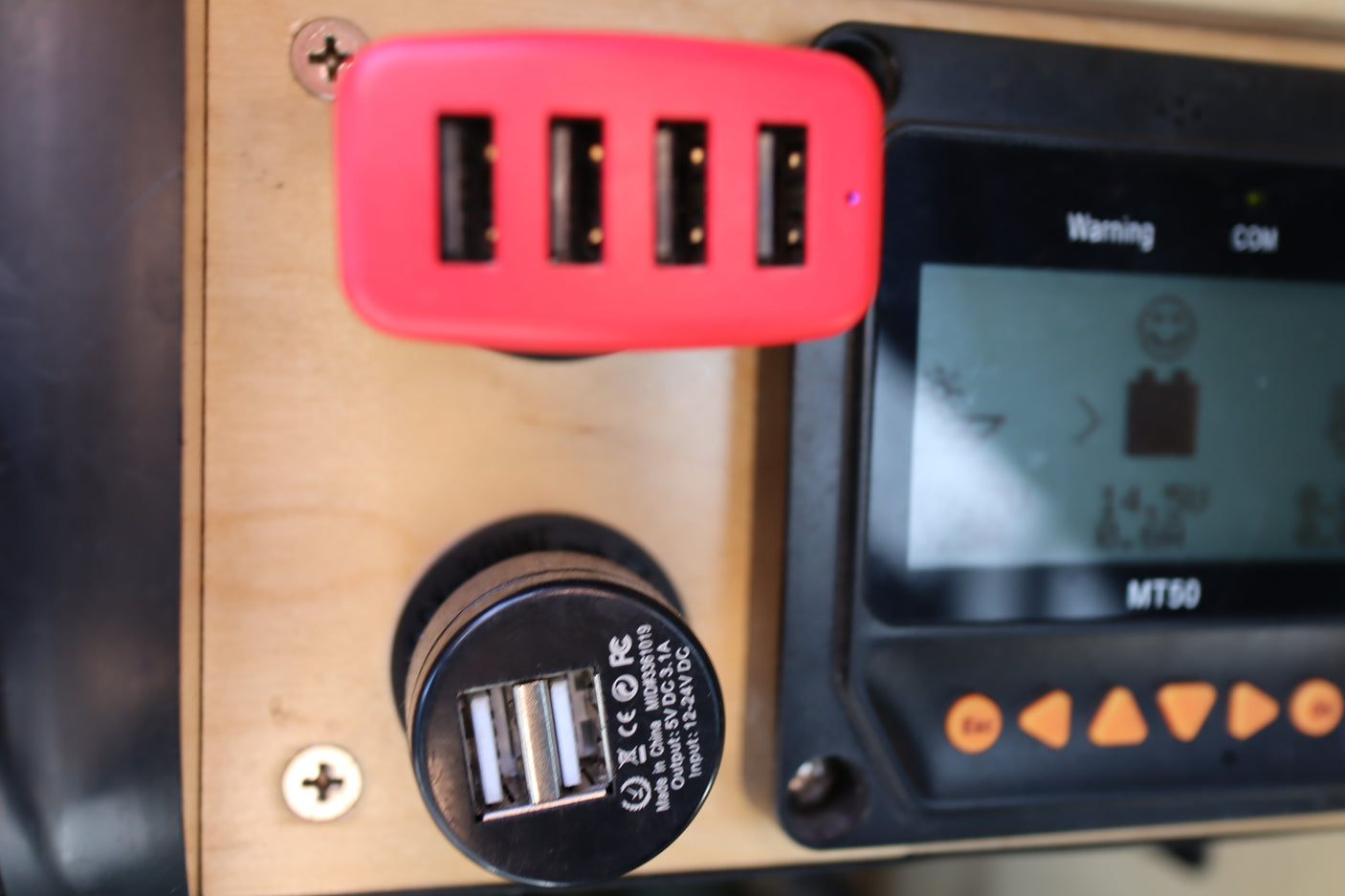 Inside an RV rental, a red 4-port USB hub, 12V dual charger, and MT50 solar controller display show power status.