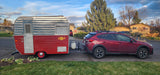 Red Subaru towing a vintage "Little Loafer" travel trailer, perfect for an RV rental adventure.