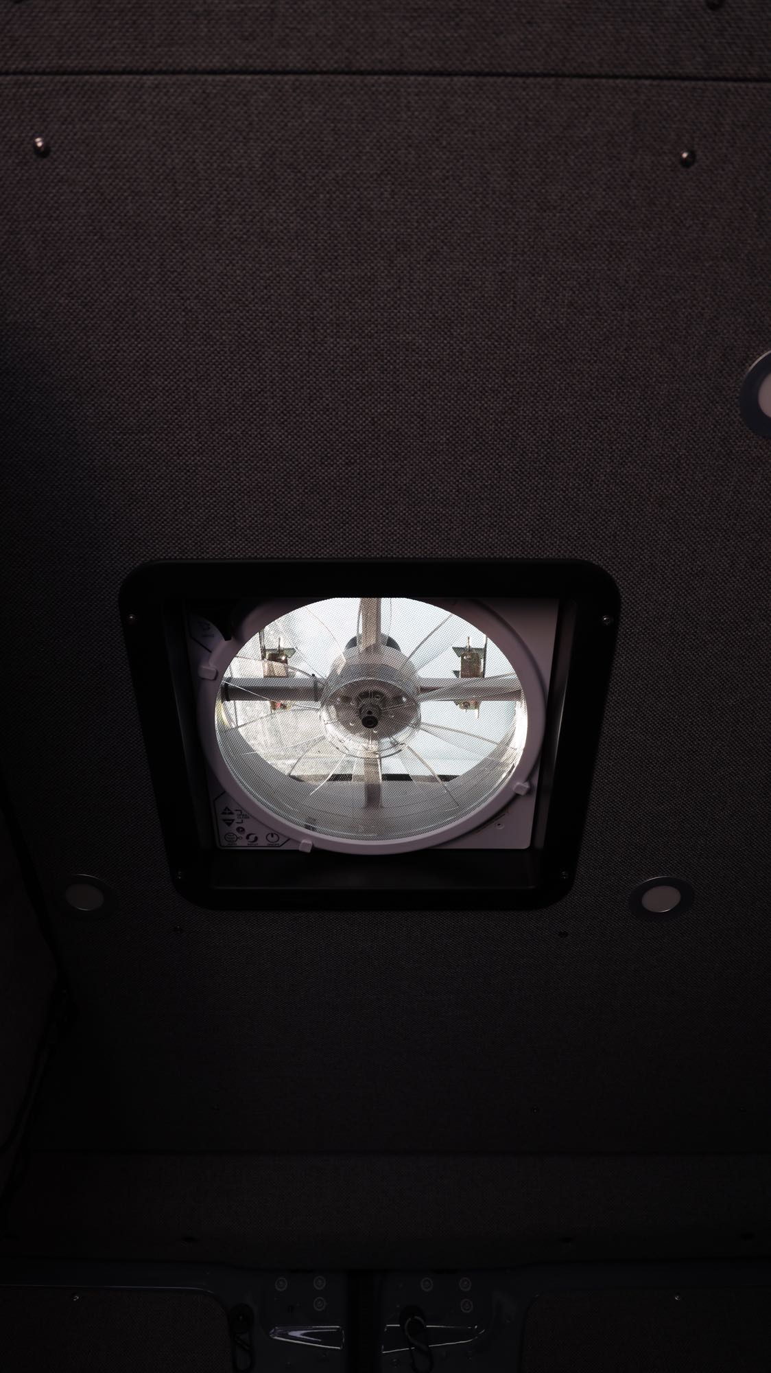 Inside an rv rental: View of the ceiling with a roof vent fan and recessed lighting.