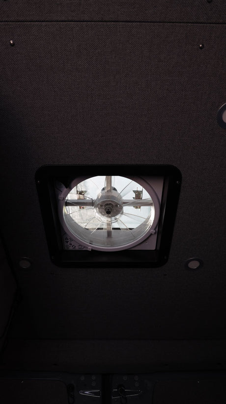 Inside an rv rental: View of the ceiling with a roof vent fan and recessed lighting.