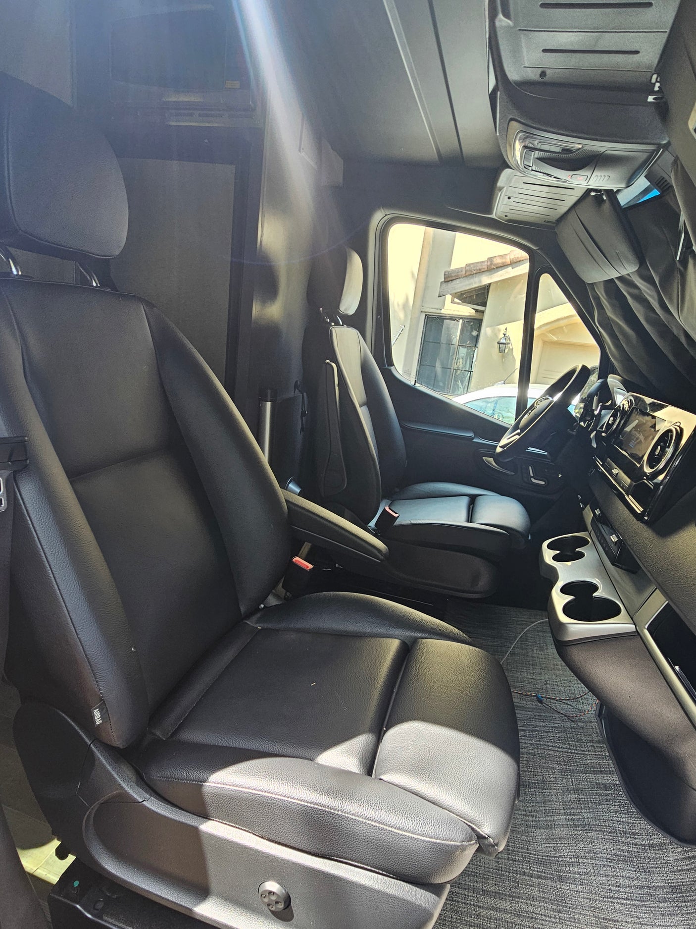Spacious RV rental interior featuring black leather seats, dashboard, and living area amenities.