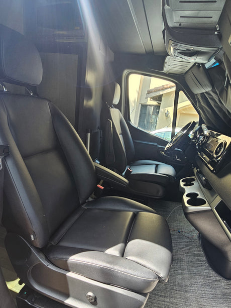 Spacious RV rental interior featuring black leather seats, dashboard, and living area amenities.