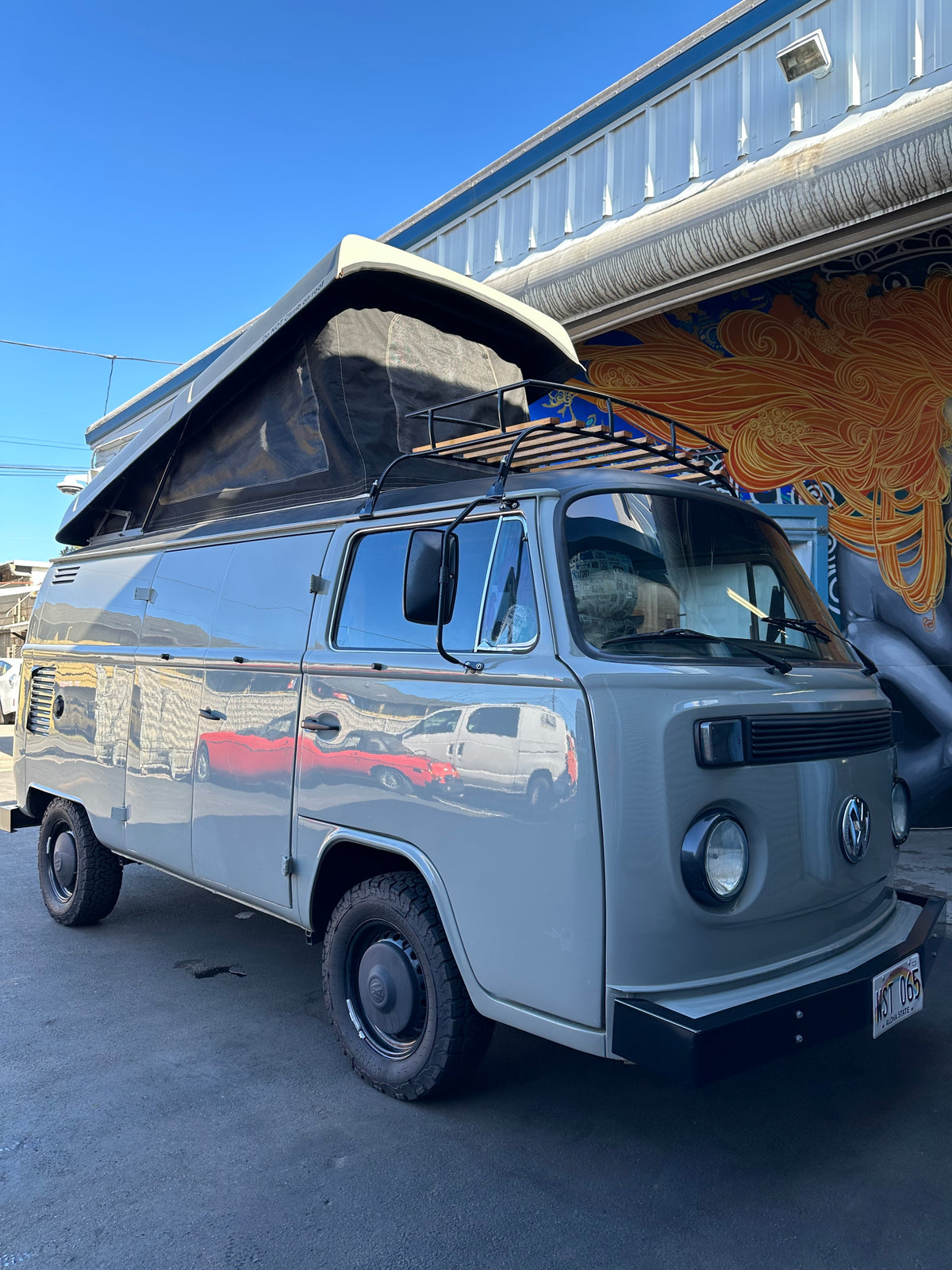 Pop-top grey VW Bus RV rental camper van with off-road tires and roof rack, parked by a vibrant mural. — photo 5