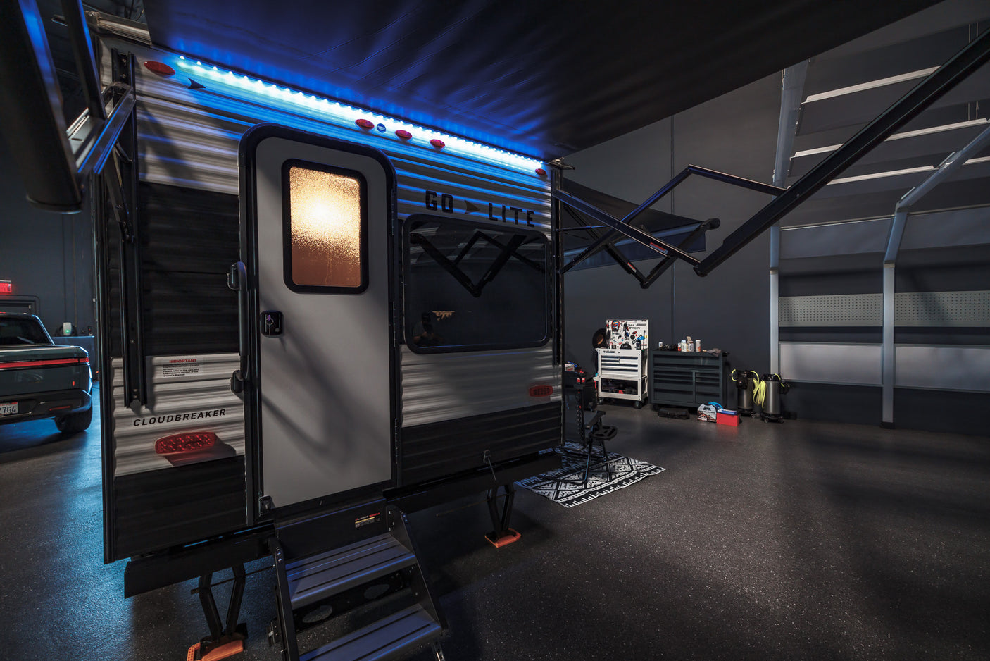 Modern Cloudbreaker travel trailer RV rental setup with LED awning lights and interior glow, parked in a spacious garage.