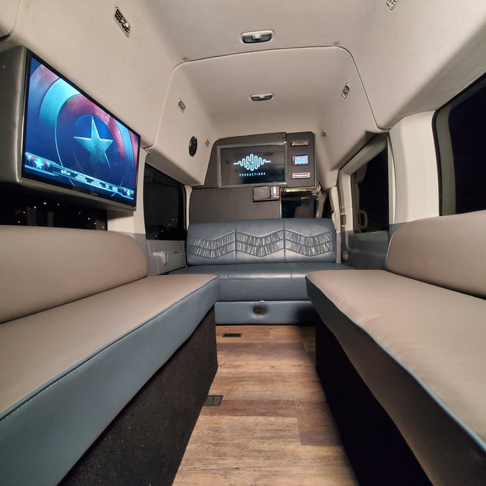 Spacious RV rental interior with comfortable seating, a large entertainment screen showing Captain America, and modern controls.