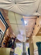 RV rental interior: A surfboard is suspended from the wood-paneled ceiling of this adventure-ready camper van.