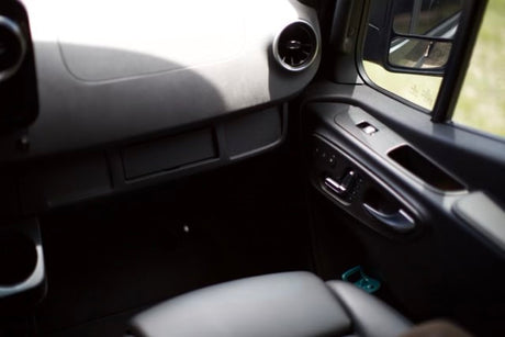 Inside your RV rental: passenger dash storage, door controls, & side mirror view.