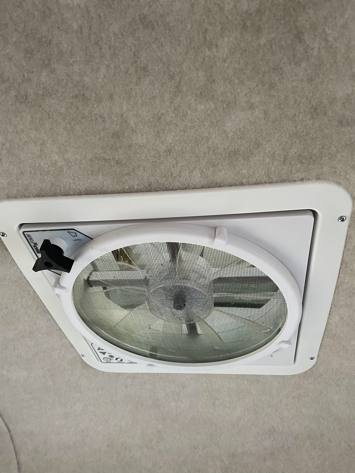 An RV rental features a Maxx-Fan ceiling vent with screen, offering fresh air. Light grey upholstered interior.