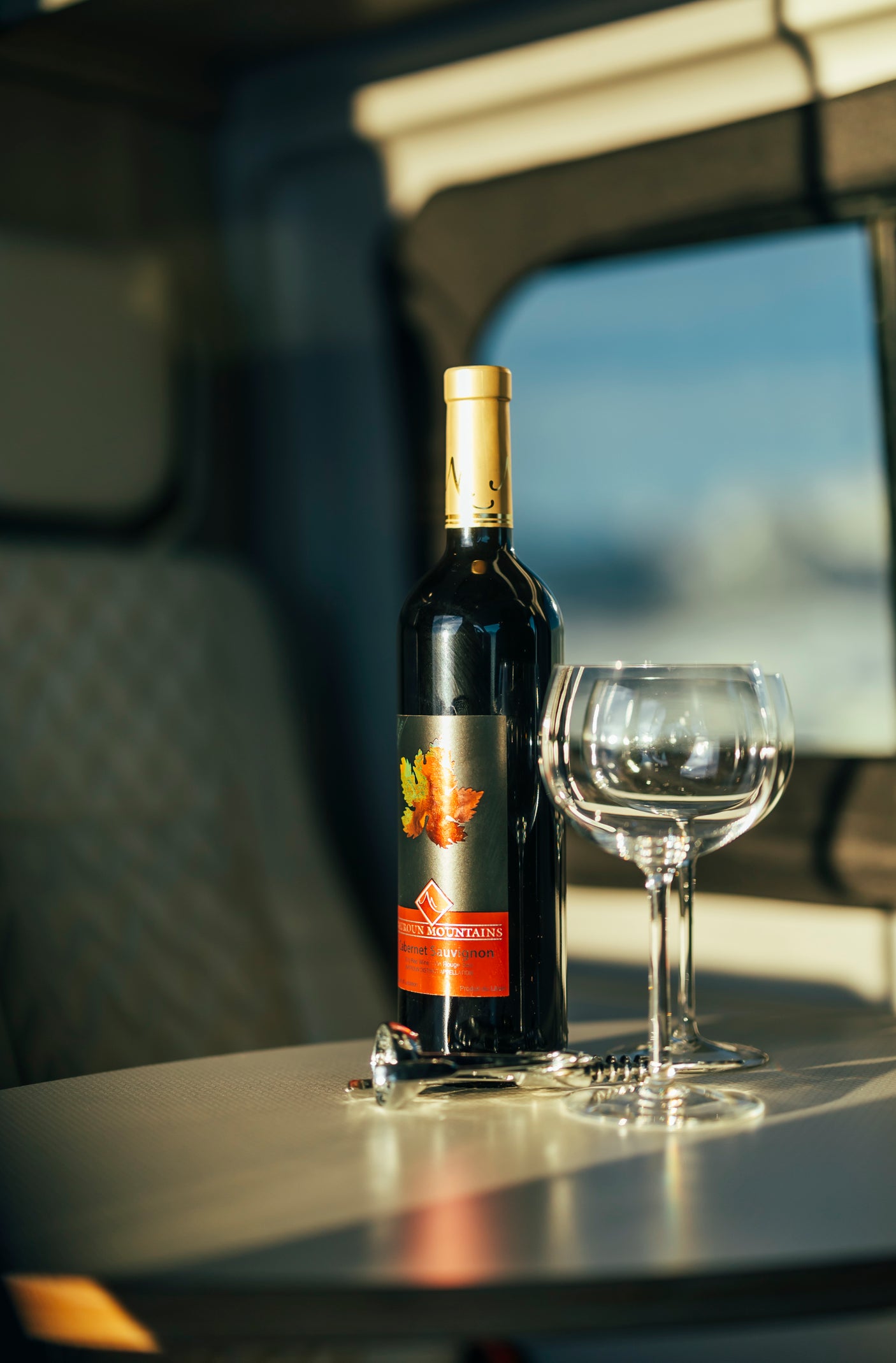 Enjoy wine on your RV rental adventure! Bottle of Green Mountains Cabernet Sauvignon, glasses, and corkscrew inside an RV.