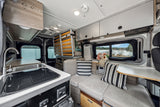 Inside a modern **RV rental**: well-equipped kitchen, plush seating, and a beautiful waterside vista for your journey.