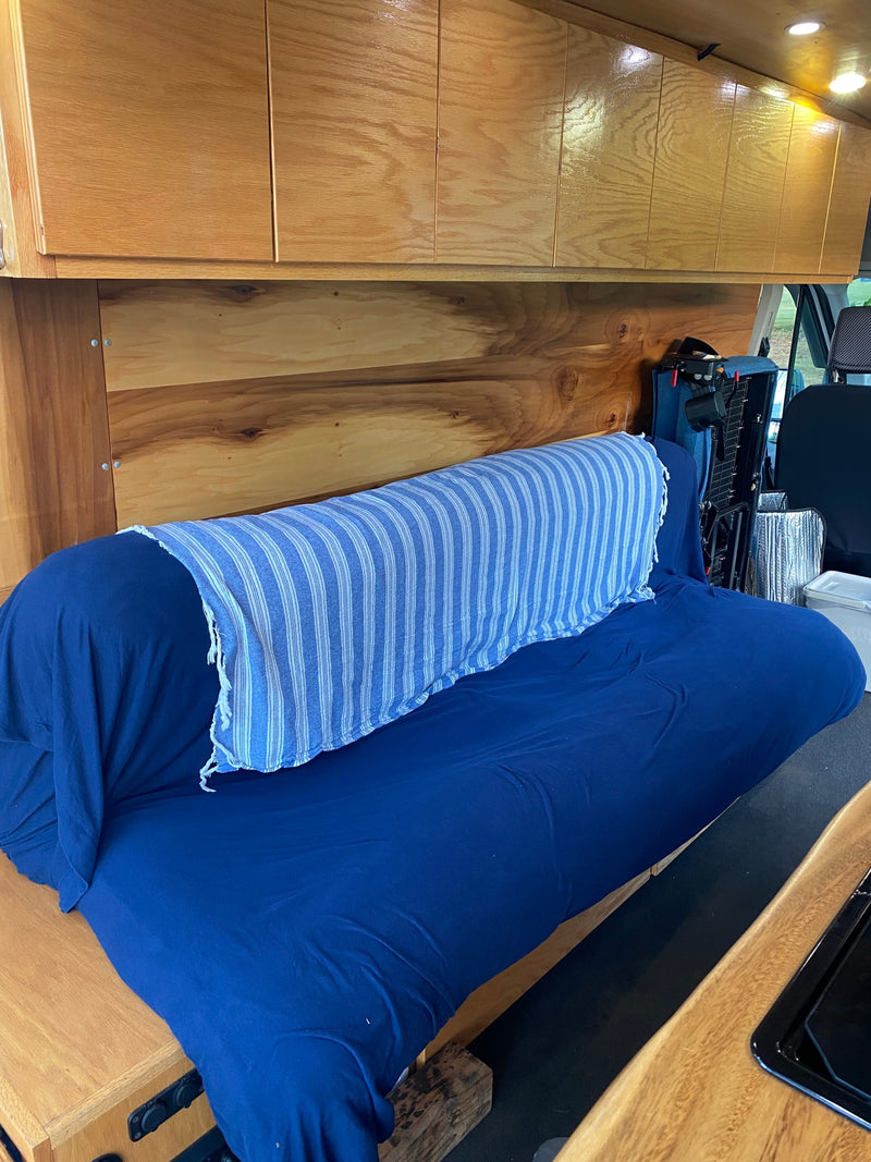 Cozy RV rental interior featuring wooden cabinets, a blue couch/bed with striped blanket, and ceiling lights. — photo 19