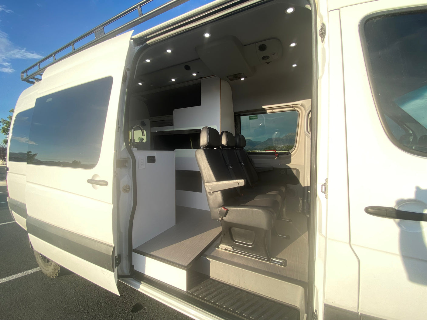 This RV rental shows a spacious, customized camper van interior with kitchen & passenger seating. Great for road trips!
