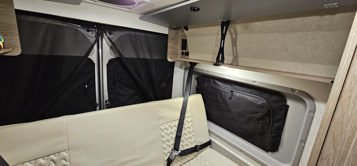 Inside a clean rv rental, showcasing a modern bench seat, practical window screens, and overhead storage with built-in lighting.