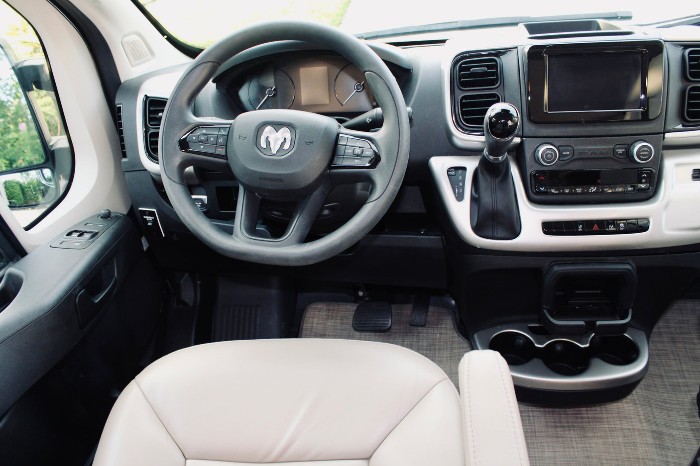 Driver's view in an RV rental: Ram ProMaster van cockpit, highlighting the steering wheel, dashboard, and central console controls.
