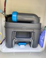 This RV rental's cassette toilet waste tank system is ready, with plumbing and blue gloves visible in the white compartment.