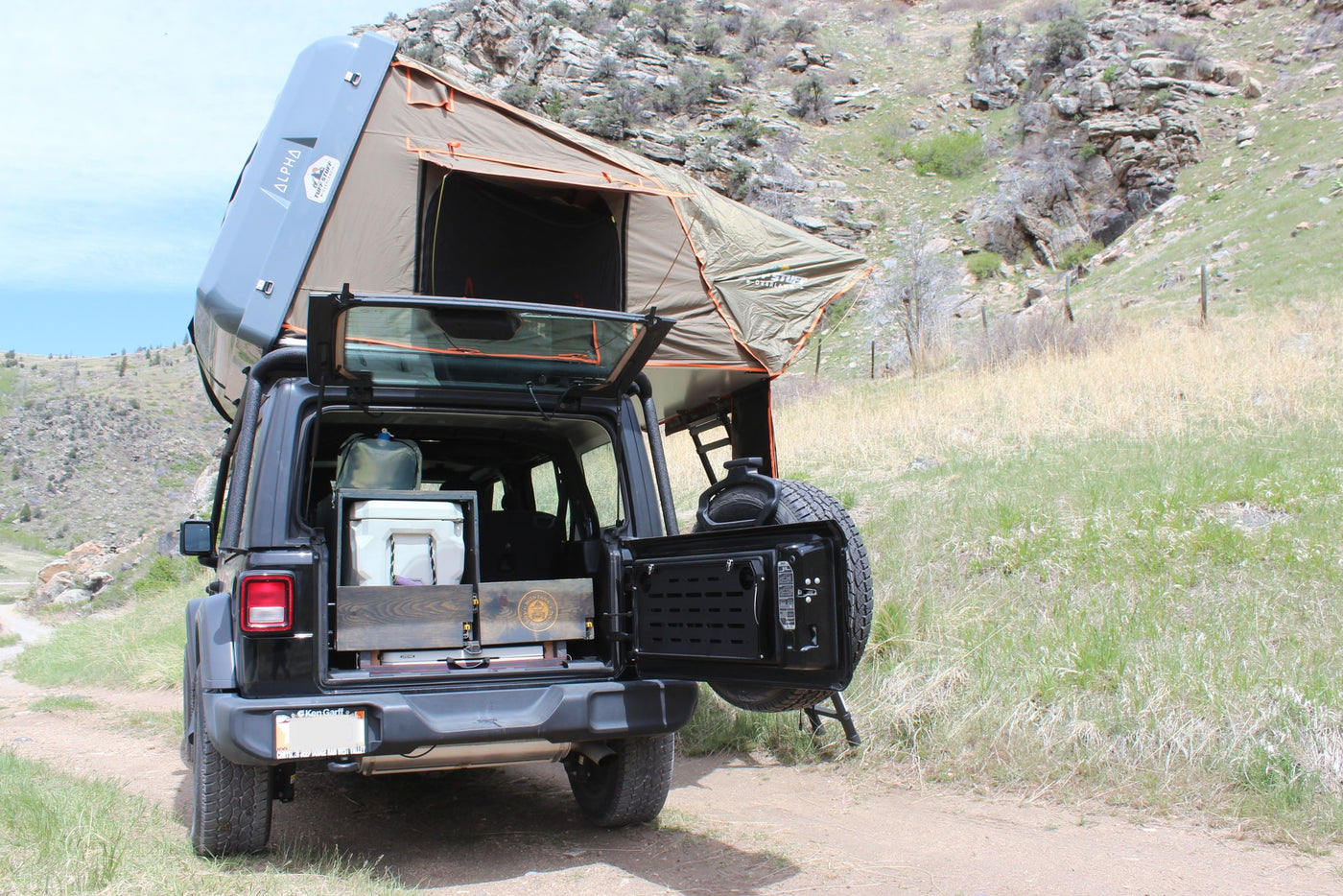 An RV rental Jeep Wrangler, equipped with a Tuff Stuff rooftop tent, ready for overlanding and camping on a dirt road. — photo 11