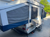 This Jayco pop-up RV camper, fully extended with an outdoor stove, offers compact comfort for your next RV rental trip or camping adventure.