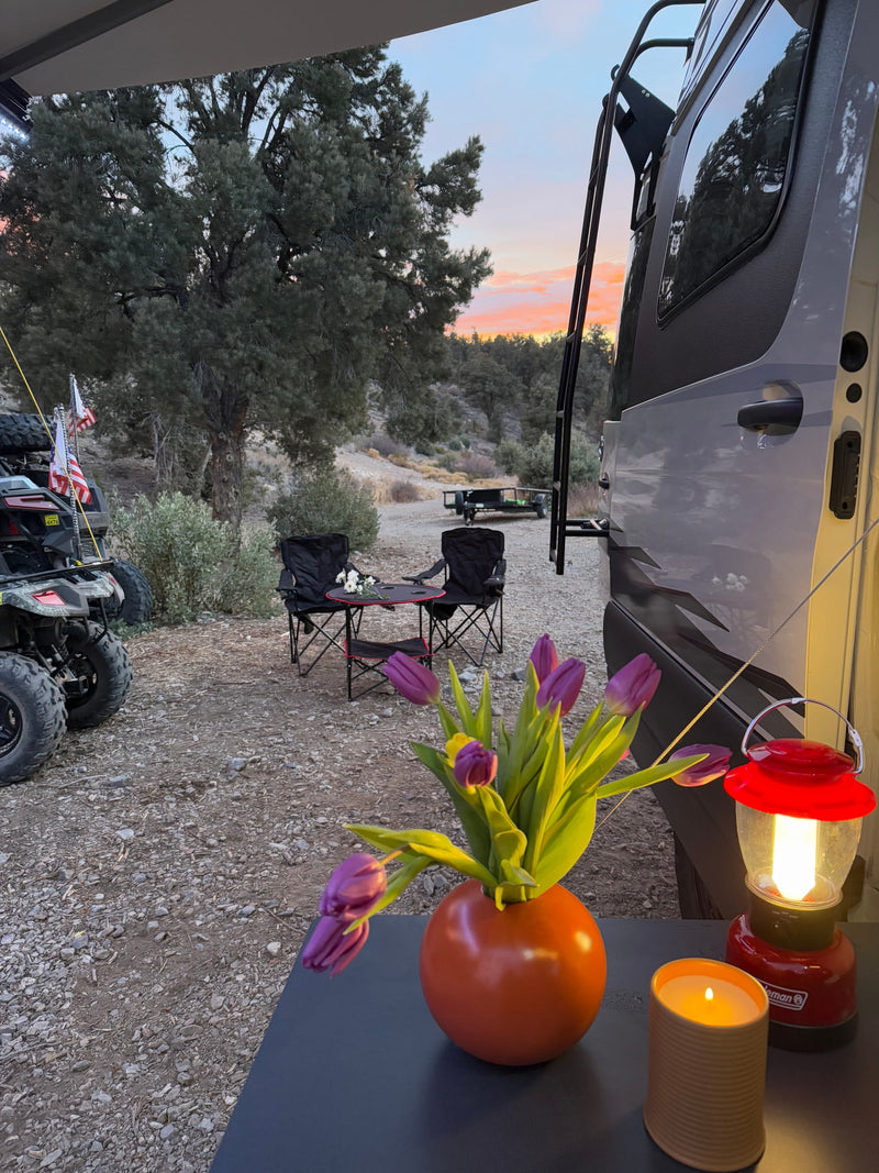 Relaxing at an RV rental campsite at sunset. Features cozy seating, floral decor, a lantern, and an ATV. — photo 9
