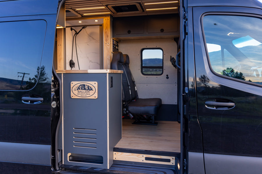 Custom Baller Adventures camper van RV rental interior: featuring a modern shower area, comfortable seating, and wood paneling.