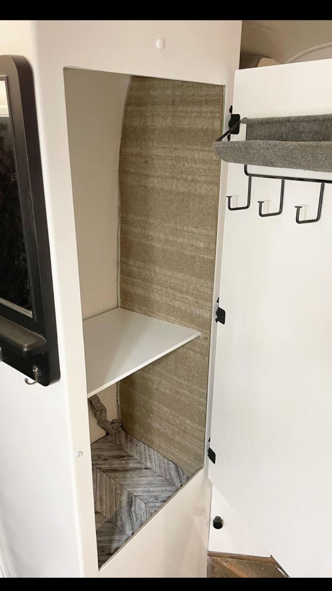 RV rental storage: Open cabinet with shelf, felt organizer, and herringbone floor for compact, organized interior.