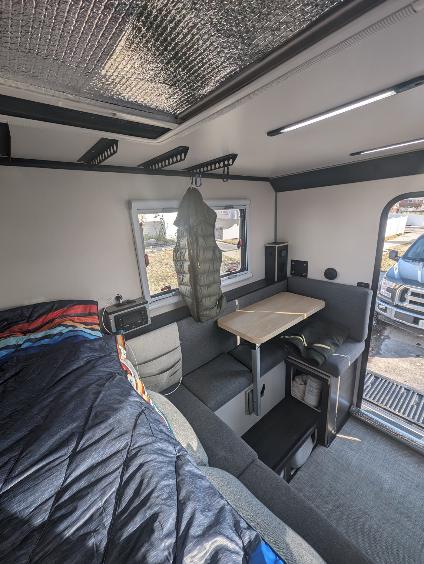 Inside an RV rental: Cozy compact interior with bed, dinette, and overhead storage. — photo 8