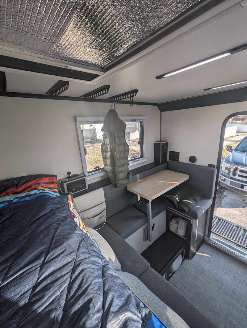 Inside an RV rental: Cozy compact interior with bed, dinette, and overhead storage. — photo 8