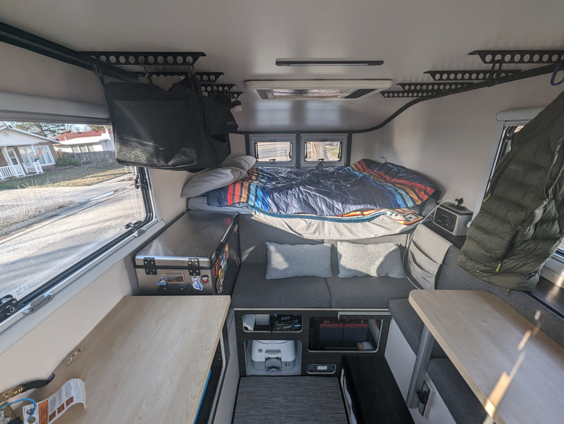 Step inside this RV rental: a compact interior featuring a comfortable bed, seating, and organized storage. — photo 3