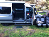  parked next to a vineyard with rolling hills and a clear sky.|Adventure-ready RV rental. Silver camper van with open doors