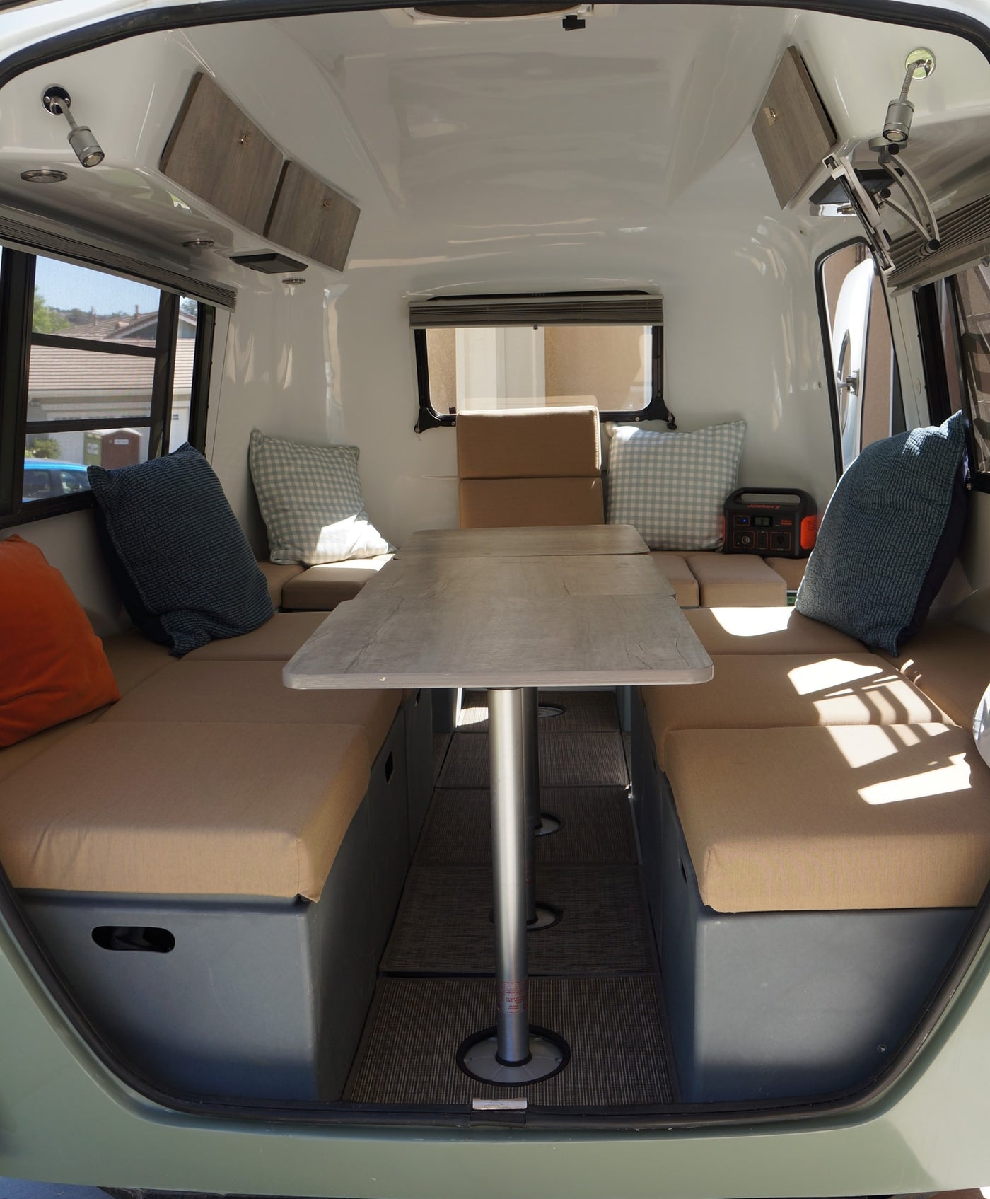 Inside an RV rental: a compact camper interior with a central table, bench seating, and windows. Ideal for travel. — photo 7
