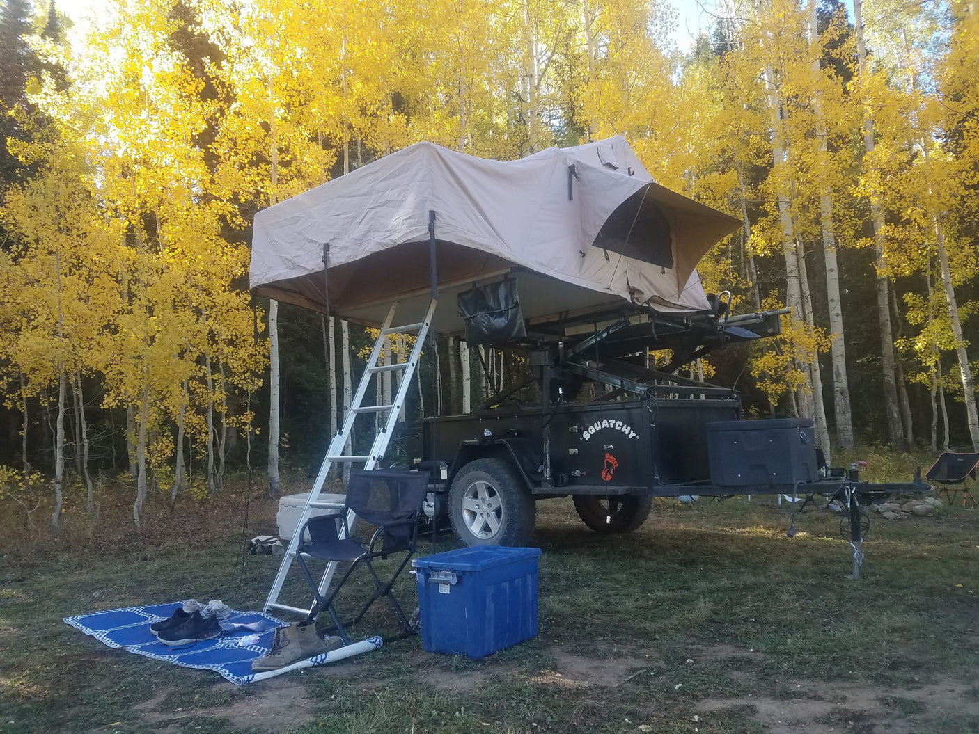 Autumn camping with a "Squatchy" RV rental and roof-top tent amidst golden aspen trees. Ideal for outdoor adventures.