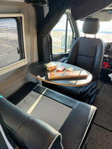 Relaxing in an RV rental: A cribbage board & cards are set on a table between two comfy seats, overlooking outside views.