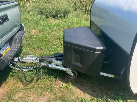 Green truck hitched to a small travel trailer, ready for an RV rental adventure in a grassy field.