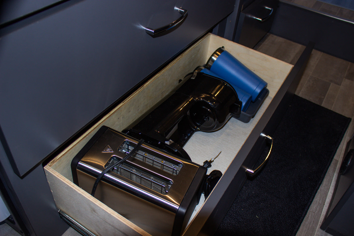 RV rental kitchen drawer with a toaster, coffee maker, and travel mug, ideal for compact travel living.