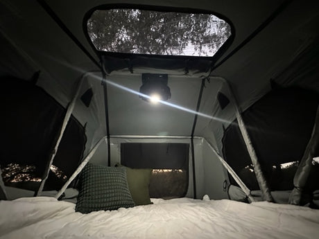 Cozy RV rental tent interior with bed, pillows, and bright overhead light for a comfortable night.