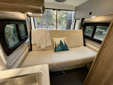 Plush sofa and scenic views from inside this spacious RV rental, ideal for a relaxing camping trip.