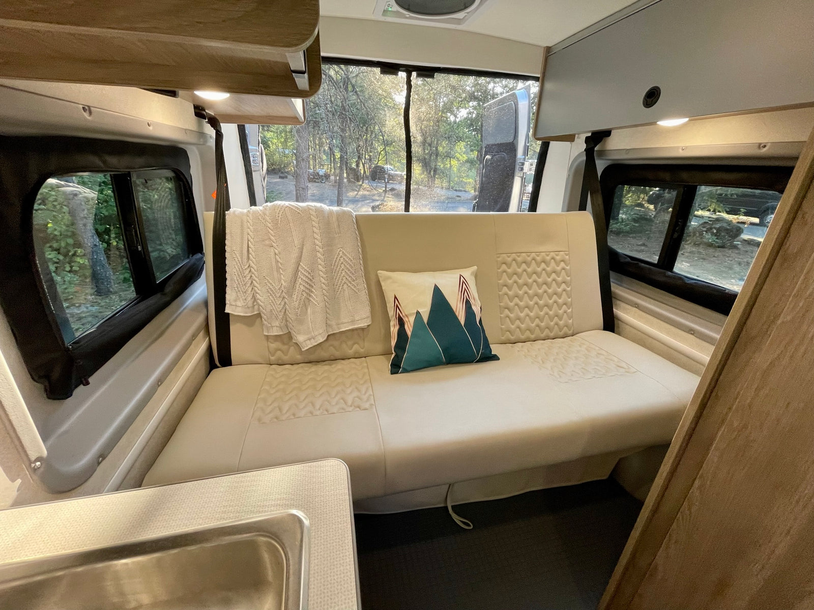 Plush sofa and scenic views from inside this spacious RV rental, ideal for a relaxing camping trip.
