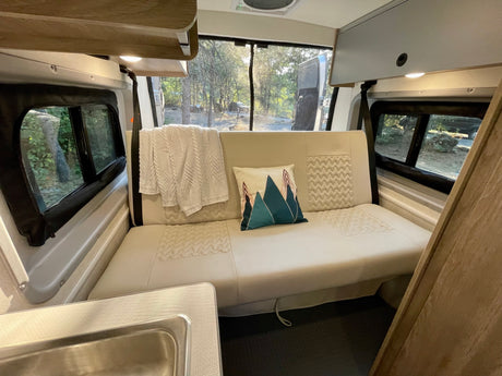 Plush sofa and scenic views from inside this spacious RV rental, ideal for a relaxing camping trip.